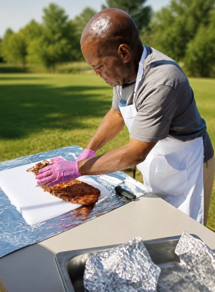 Demetrius preparing barbecue ribs outdoors